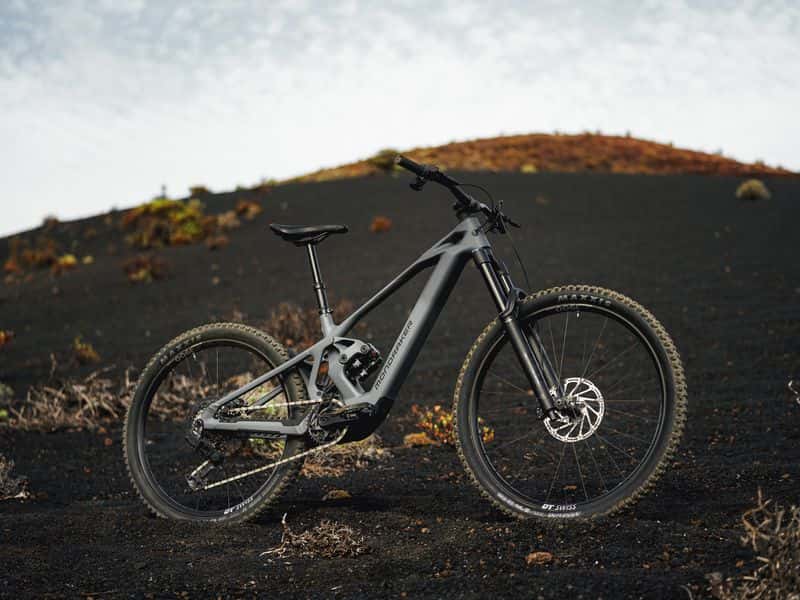 Grey Mondraker Zendit e-MTB with Avinox M2S motor standing on dark volcanic terrain