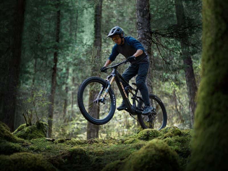 Rider on an Avinox-powered e-MTB on a mossy forest trail