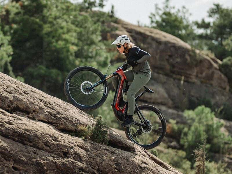 Rider climbing a rock slab on a Cannondale Moterra e-mountain bike with Horst-link rear suspension