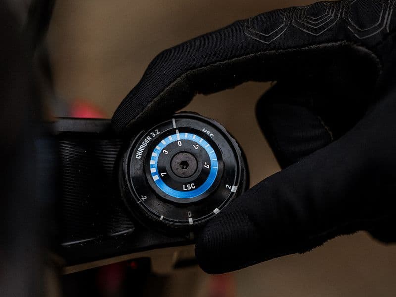 Rider turning the low-speed compression dial on a RockShox Charger 3.2 fork damper