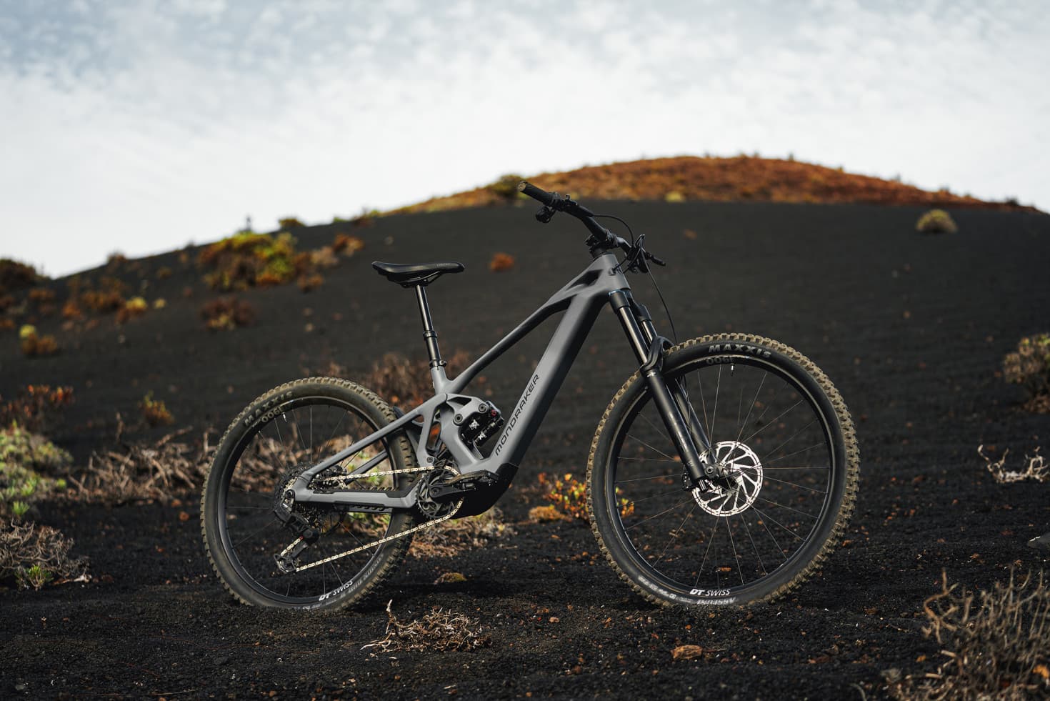 Grey Mondraker Zendit e-MTB with Avinox M2S motor standing on dark volcanic terrain