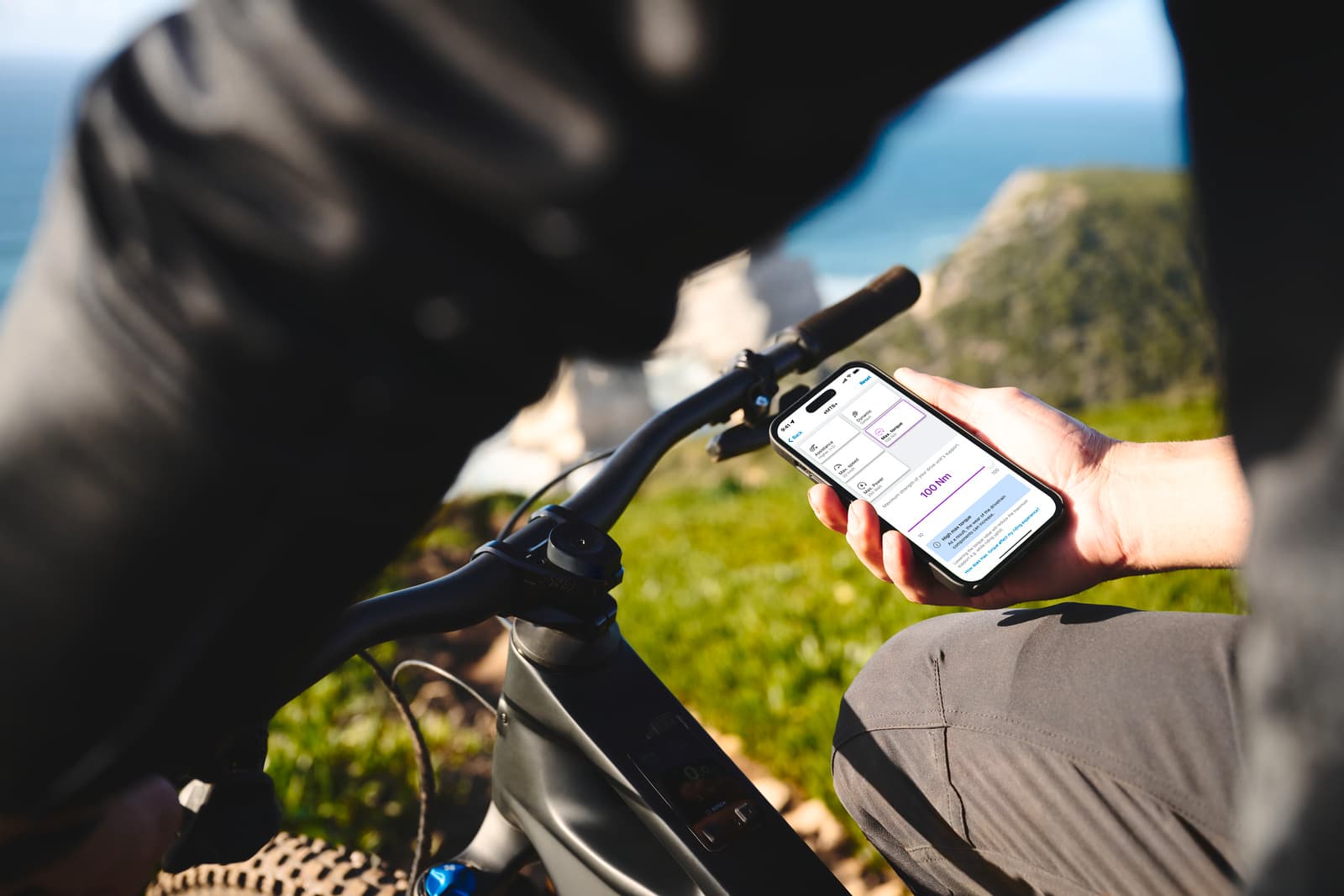 Rider checking the Bosch eBike Flow app on a smartphone next to a Bosch-powered e-MTB