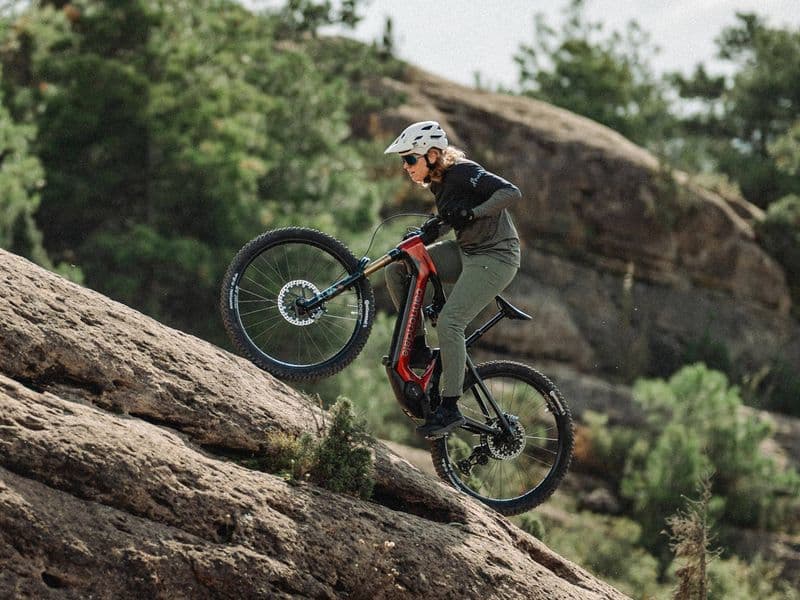 Rider climbing a rock slab on a Cannondale Moterra e-mountain bike with Horst-link rear suspension