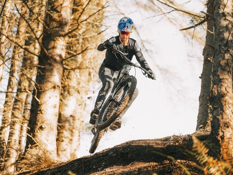 Rider jumping a carbon Mondraker Zendit e-MTB in a forest