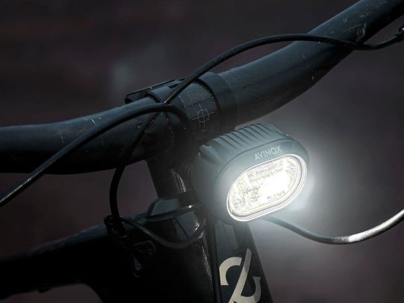 Avinox Front Light switched on, mounted on an e-MTB handlebar at dusk