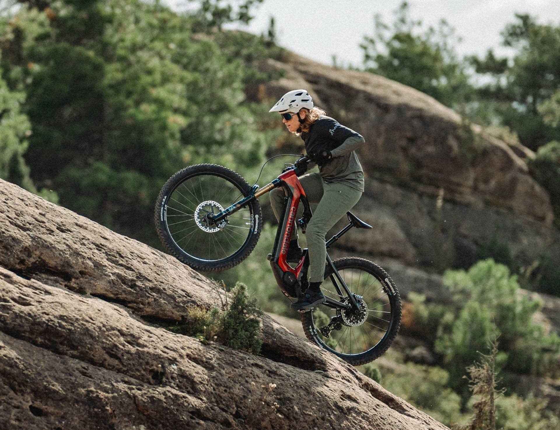Rider climbing a rock slab on a Cannondale Moterra e-mountain bike with Horst-link rear suspension