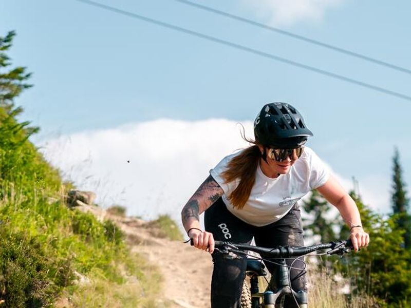 Rider descending a meadow trail in Saalbach with a gondola in the background