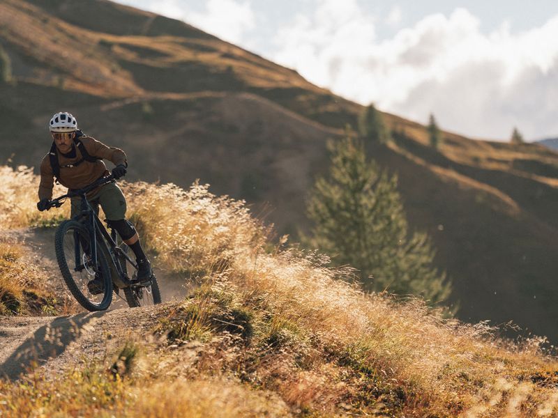 Enduro rider on a singletrack through autumn grass in Livigno