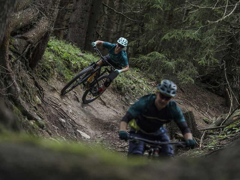 Two riders on a rooty forest singletrack in Bike Kingdom Lenzerheide