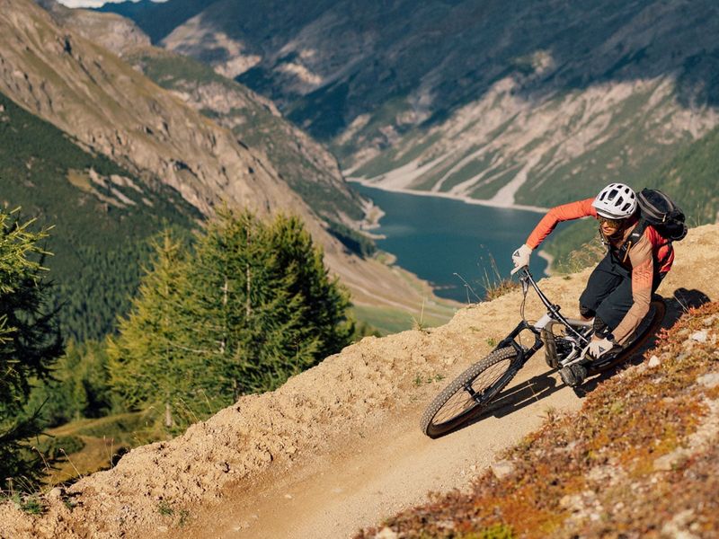 Rider cornering a berm on a flow trail above Lake Livigno