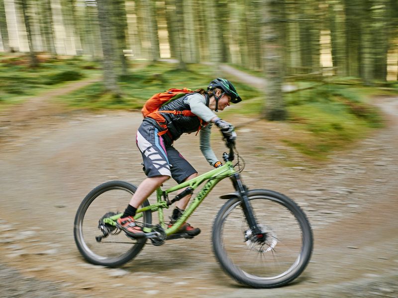 Mountain biker cornering on a gravel berm at Glentress