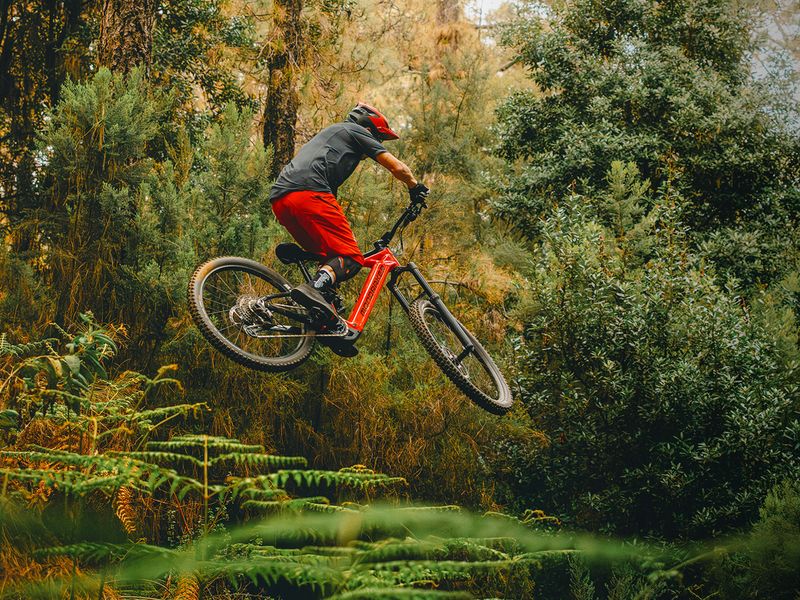 Rider jumping a Mondraker Level e-MTB in the forest