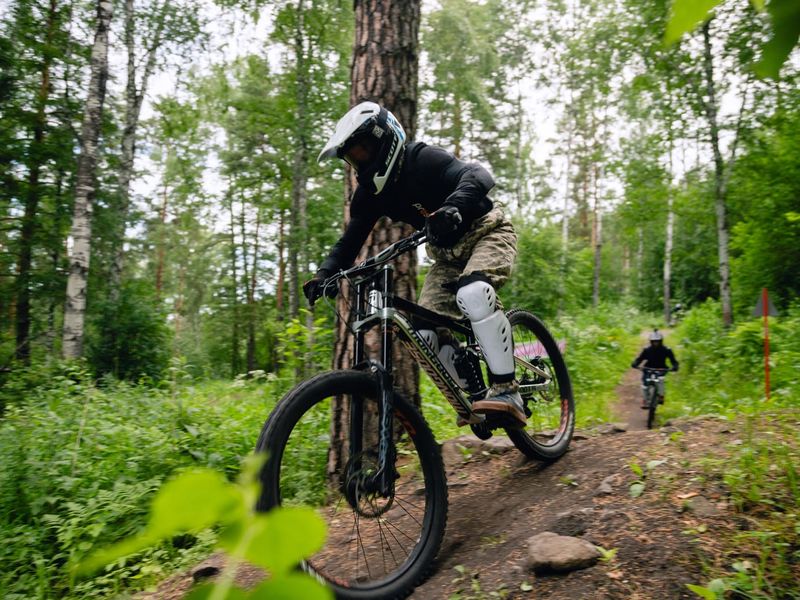 Downhill rider on a forest trail at Manzherok bike park, Altai