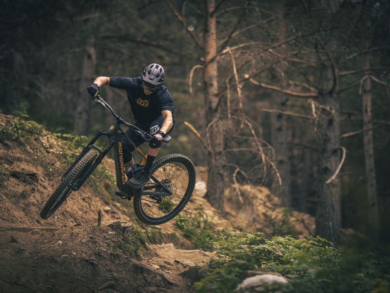 Rider jumping a Mondraker Neat light e-MTB in the forest