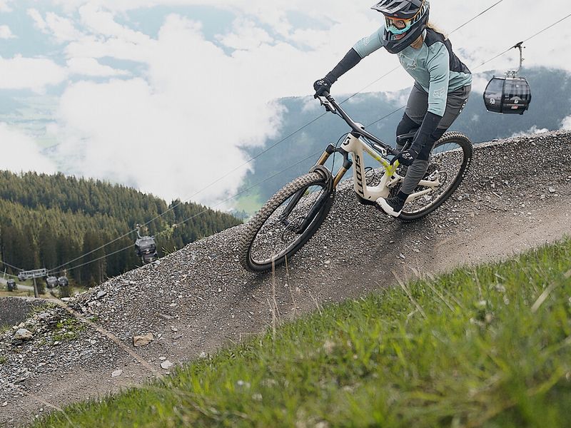 Rider on a berm in Bikepark Leogang with a chairlift behind