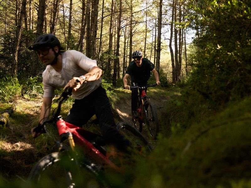 Riders on red Mondraker Neat e-MTBs on a forest trail