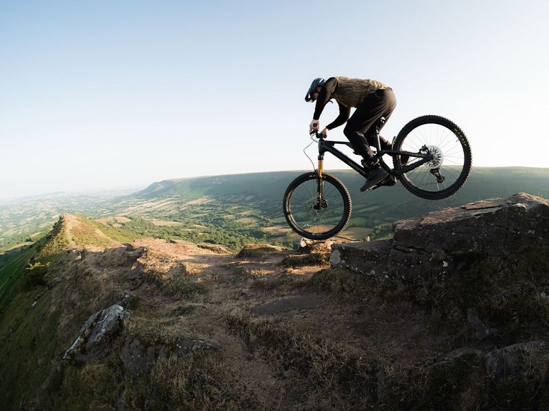 Rider jumping a Whyte Karve RSX Avinox eMTB off a rock on a ridge
